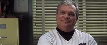 Movie still from “The Rookie” (2002), directed by John Lee Hancock – An older man wearing a baseball uniform smiling for the camera; Close Up shot, Low angle