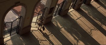 Movie still from “The Rookie” (2002), directed by John Lee Hancock – A person walking on a sidewalk near a metal gate; Extreme Wide shot, High angle