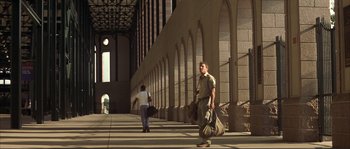 Movie still from “The Rookie” (2002), directed by John Lee Hancock – A man walking down a sidewalk carrying luggage; Wide shot, Low angle