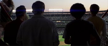 Movie still from “The Rookie” (2002), directed by John Lee Hancock – Two men are watching a baseball game from the bleachers; Wide shot, Low angle