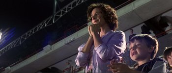 Movie still from “The Rookie” (2002), directed by John Lee Hancock – A woman standing in front of an audience with her hands clasped; Medium shot, Low angle