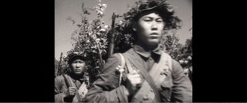 Movie still from “The Sacrifice” (2020), directed by Yang Lu – A man in a field holding a rifle and another man in a hat; Close Up shot, Low angle