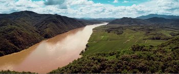 Movie still from “The Sacrifice” (2020), directed by Yang Lu – A view of a river and a mountain range in the distance; Extreme Wide shot, High angle