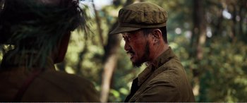 Movie still from “The Sacrifice” (2020), directed by Yang Lu – A man with a beard wearing a hat and jacket; Close Up shot, Over the shoulder angle