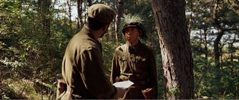 Movie still from “The Sacrifice” (2020), directed by Yang Lu – Two men in military uniforms talking in the woods; Medium shot, Over the shoulder angle
