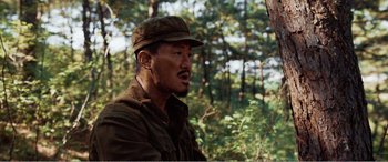 Movie still from “The Sacrifice” (2020), directed by Yang Lu – A man wearing a hat in the woods; Close Up shot, Over the shoulder angle