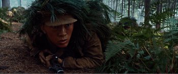 Movie still from “The Sacrifice” (2020), directed by Yang Lu – A man with a hat and a rifle in the woods; Medium shot, High angle