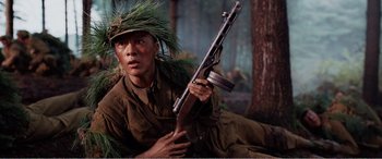 Movie still from “The Sacrifice” (2020), directed by Yang Lu – A man with a rifle in a forest; Medium shot, High angle
