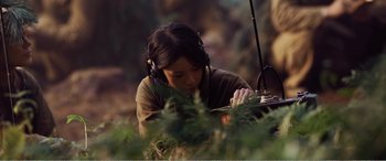 Movie still from “The Sacrifice” (2020), directed by Yang Lu – A woman wearing headphones looking down at a book; Medium shot, High angle