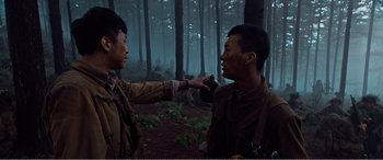 Movie still from “The Sacrifice” (2020), directed by Yang Lu – Two men in the woods one of which is holding a camera; Medium shot, Over the shoulder angle