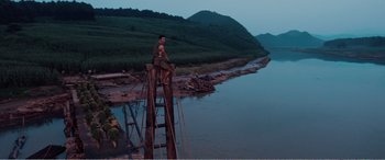 Movie still from “The Sacrifice” (2020), directed by Yang Lu – A man sitting on top of a wooden bridge; Extreme Wide shot, Low angle