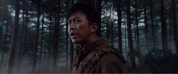 Movie still from “The Sacrifice” (2020), directed by Yang Lu – A man standing in the middle of a forest; Close Up shot, Low angle