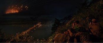 Movie still from “The Sacrifice” (2020), directed by Yang Lu – A person sitting on a rock looking at a river; Extreme Wide shot, High angle