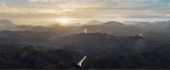 Movie still from “The Sacrifice” (2020), directed by Yang Lu – The sun is setting over a mountain range; Extreme Wide shot, High angle