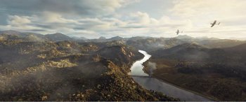 Movie still from “The Sacrifice” (2020), directed by Yang Lu – An aerial view of a river flowing through a lush green landscape; Extreme Wide shot, High angle