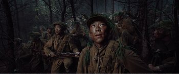 Movie still from “The Sacrifice” (2020), directed by Yang Lu – A group of men in military fatigues are standing in the woods; Medium shot, Low angle