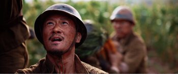 Movie still from “The Sacrifice” (2020), directed by Yang Lu – A man wearing a helmet and a camouflage shirt; Close Up shot, Low angle