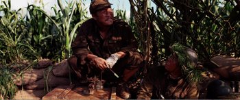 Movie still from “The Sacrifice” (2020), directed by Yang Lu – A man sitting on the ground with a knife in his hand; Medium shot, High angle
