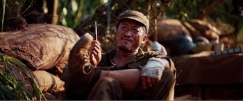 Movie still from “The Sacrifice” (2020), directed by Yang Lu – A man sitting on the ground holding a knife; Close Up shot, Low angle