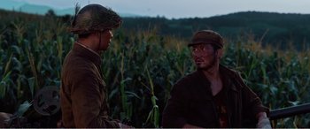 Movie still from “The Sacrifice” (2020), directed by Yang Lu – Two men are talking in a field of corn; Medium shot, Over the shoulder angle