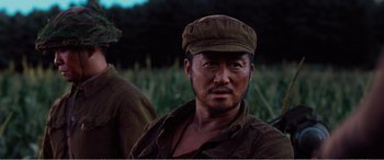 Movie still from “The Sacrifice” (2020), directed by Yang Lu – A person wearing a hat near some grass; Close Up shot, Low angle