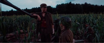 Movie still from “The Sacrifice” (2020), directed by Yang Lu – Two men in a field talking to each other; Medium shot, Low angle