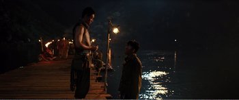 Movie still from “The Sacrifice” (2020), directed by Yang Lu – Two men standing next to each other near the water; Medium shot, Over the shoulder angle