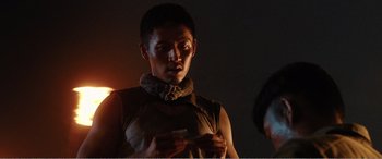 Movie still from “The Sacrifice” (2020), directed by Yang Lu – A man in a brown shirt is looking at a camera; Medium shot, Over the shoulder angle