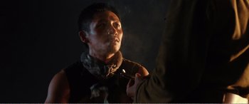Movie still from “The Sacrifice” (2020), directed by Yang Lu – A man smoking a pipe while wearing a scarf; Close Up shot, Over the shoulder angle