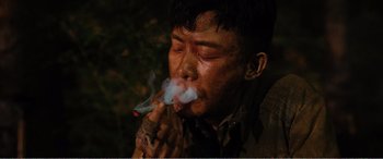 Movie still from “The Sacrifice” (2020), directed by Yang Lu – A man smoking a cigarette in the dark; Close Up shot, High angle