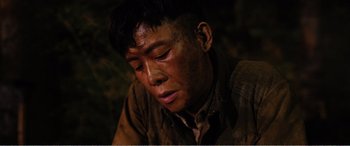 Movie still from “The Sacrifice” (2020), directed by Yang Lu – A man in a brown shirt is looking down at his face; Close Up shot, High angle
