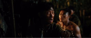 Movie still from “The Sacrifice” (2020), directed by Yang Lu – A man sitting next to another man in a dark room; Close Up shot, High angle