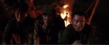 Movie still from “The Sacrifice” (2020), directed by Yang Lu – A group of men sitting next to each other in front of a fire; Medium shot, High angle