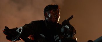 Movie still from “The Sacrifice” (2020), directed by Yang Lu – A man in a black shirt is holding a gun; Close Up shot, Low angle