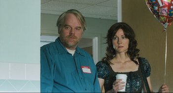 Movie still from “The Savages” (2007), directed by Tamara Jenkins – A man and a woman standing next to each other holding a cup; Medium shot, Over the shoulder angle
