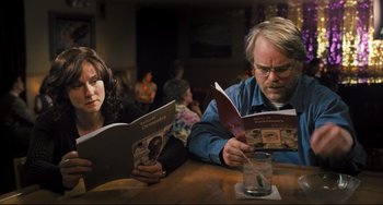 Movie still from “The Savages” (2007), directed by Tamara Jenkins – A man and a woman sitting at a wooden table; Close Up shot, Over the shoulder angle