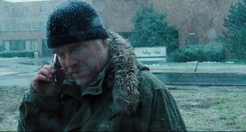 Movie still from “The Savages” (2007), directed by Tamara Jenkins – A man with a beard wearing a green jacket and a black hat; Close Up shot, Over the shoulder angle