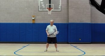 Movie still from “The Savages” (2007), directed by Tamara Jenkins – A man holding a tennis racquet on a tennis court; Wide shot, Low angle
