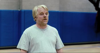 Movie still from “The Savages” (2007), directed by Tamara Jenkins – A man with blonde hair is standing in a gym; Medium shot, Over the shoulder angle