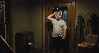 Movie still from “The Savages” (2007), directed by Tamara Jenkins – A man standing in front of a door with his hand on his head; Medium shot, Over the shoulder angle