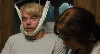 Movie still from “The Savages” (2007), directed by Tamara Jenkins – A man wearing a head brace while standing next to a woman; Close Up shot, Over the shoulder angle