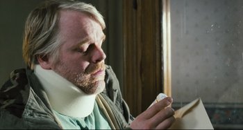 Movie still from “The Savages” (2007), directed by Tamara Jenkins – A man wearing a neck brace holding a piece of paper; Close Up shot, Over the shoulder angle