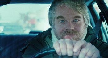 Movie still from “The Savages” (2007), directed by Tamara Jenkins – A person sitting in a car holding a steering wheel; Close Up shot, Over the shoulder angle