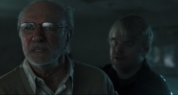 Movie still from “The Savages” (2007), directed by Tamara Jenkins – Two people in a dark room looking at the camera; Close Up shot, Over the shoulder angle
