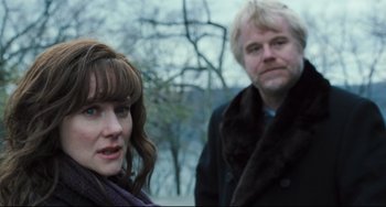 Movie still from “The Savages” (2007), directed by Tamara Jenkins – A man and a woman standing next to each other in front of trees; Close Up shot, Over the shoulder angle