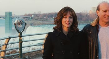 Movie still from “The Savages” (2007), directed by Tamara Jenkins – A woman standing next to a waterfall on a sunny day; Medium shot, Over the shoulder angle