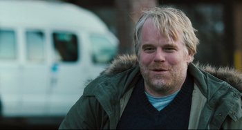 Movie still from “The Savages” (2007), directed by Tamara Jenkins – Philip seymour hoffman smiling for the camera; Close Up shot, Over the shoulder angle