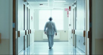 Movie still from “The Savages” (2007), directed by Tamara Jenkins – A man in a white robe walking down a hallway; Wide shot, Low angle