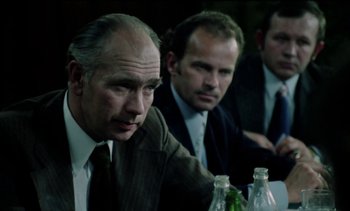 Movie still from “The Scar” (1976), directed by Krzysztof Kieslowski – A group of men in suits sitting at a table; Close Up shot, Over the shoulder angle