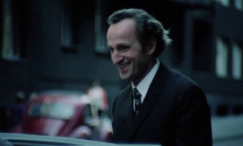 Movie still from “The Scar” (1976), directed by Krzysztof Kieslowski – A man in a suit and tie smiling for the camera; Close Up shot, Low angle